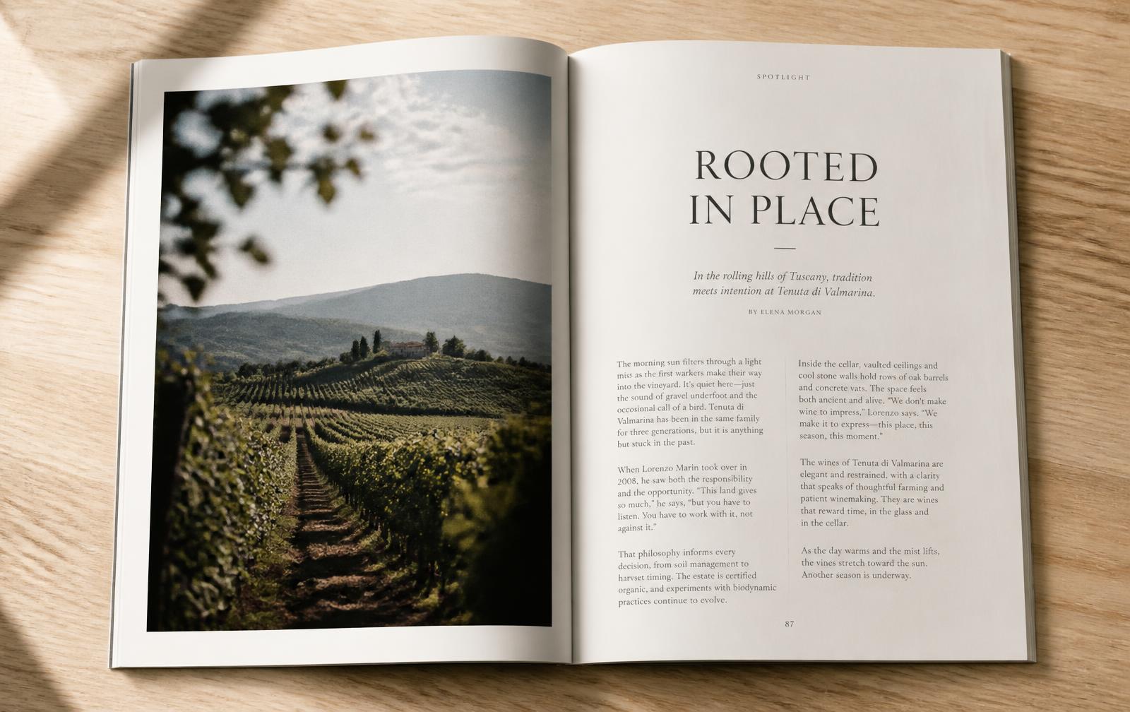 THE EDIT lying open on an oak table, showing an interior feature spread with a full-page vineyard photograph